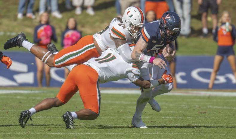 Oct 29, 2022; Charlottesville, Virginia, USA; Miami Hurricanes defensive lineman Antonio Moultrie (44) and Miami Hurricanes linebacker Corey Flagg Jr. hang on to Virginia Cavaliers quarterback Brennan Armstrong in the first half (11) at Scott Stadium. Mandatory Credit: Lee Luther Jr.-USA TODAY Sports