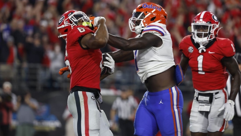 Oct 29, 2022; Jacksonville, Florida, USA; Georgia Bulldogs running back Kenny McIntosh (6) runs the ball in for a touchdown as Florida Gators linebacker Brenton Cox Jr. (1) defends during the second half at TIAA Bank Field. Mandatory Credit: Kim Klement-USA TODAY Sports