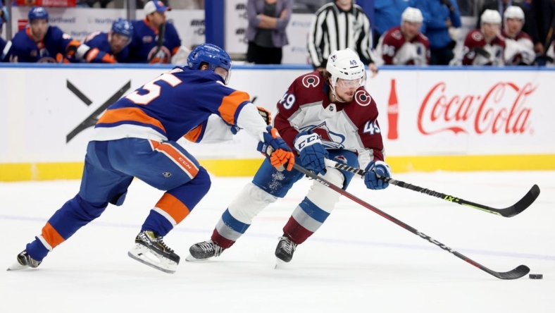 Oct 29, 2022; Elmont, New York, USA; Colorado Avalanche defenseman Samuel Girard (49) and New York Islanders defenseman Sebastian Aho (25) fight for the puck during the first period at UBS Arena. Mandatory Credit: Brad Penner-USA TODAY Sports
