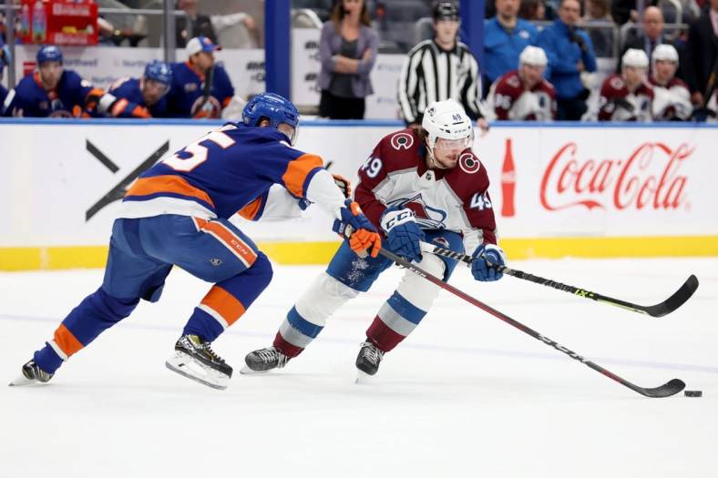 Oct 29, 2022; Elmont, New York, USA; Colorado Avalanche defenseman Samuel Girard (49) and New York Islanders defenseman Sebastian Aho (25) fight for the puck during the first period at UBS Arena. Mandatory Credit: Brad Penner-USA TODAY Sports