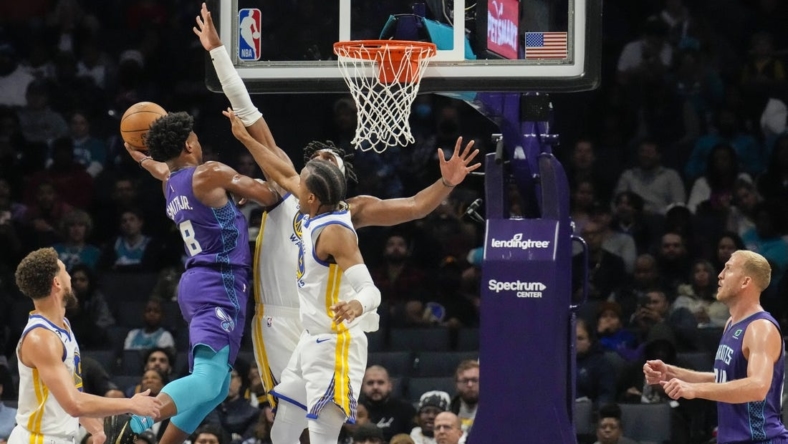 Oct 29, 2022; Charlotte, North Carolina, USA; Charlotte Hornets guard Dennis Smith Jr. (8) goes up for a shot against Golden State Warriors center Kevon Looney (5) and forward Jonathan Kuminga (00) during the second quarter at Spectrum Center. Mandatory Credit: Jim Dedmon-USA TODAY Sports