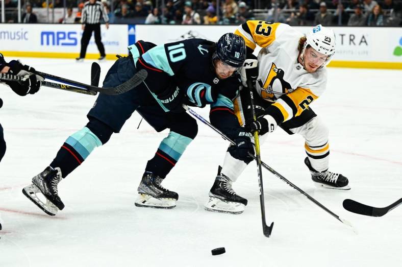 Oct 29, 2022; Seattle, Washington, USA; Seattle Kraken center Matty Beniers (10) and Pittsburgh Penguins left wing Brock McGinn (23) fight for the puck during the second period at Climate Pledge Arena. Mandatory Credit: Steven Bisig-USA TODAY Sports