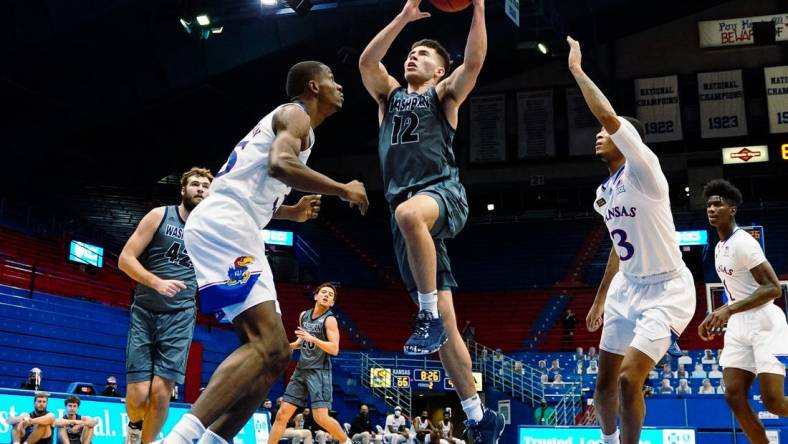 Dec 3, 2020; Lawrence, Kansas, USA; Washburn Ichabods guard Tyler Geiman (12) shoots against Kansas Jayhawks forward Gethro Muscadin (35) and guard Dajuan Harris (3) during the second half at Allen Fieldhouse. Mandatory Credit: Jay Biggerstaff-USA TODAY Sports