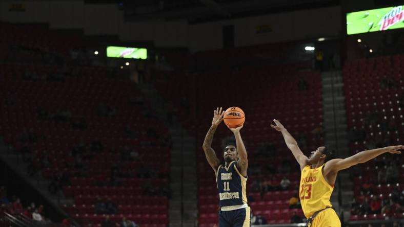 Nov 11, 2021; College Park, Maryland, USA; George Washington Colonials guard James Bishop (11) shoots a three point shot over Maryland Terrapins guard Ian Martinez (23) in the first half at Xfinity Center. Mandatory Credit: Tommy Gilligan-USA TODAY Sports