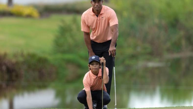 Dec 18, 2021; Orlando, Florida, USA; Charlie Woods and his dad Tiger Woods lining his putt up on the 16th green during the first round of the PNC Championship golf tournament at Grande Lakes Orlando Course. Mandatory Credit: Jeremy Reper-USA TODAY Sports