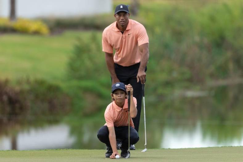 Dec 18, 2021; Orlando, Florida, USA; Charlie Woods and his dad Tiger Woods lining his putt up on the 16th green during the first round of the PNC Championship golf tournament at Grande Lakes Orlando Course. Mandatory Credit: Jeremy Reper-USA TODAY Sports