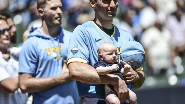 Jun 26, 2022; Milwaukee, Wisconsin, USA; Milwaukee Brewers pitcher Brent Suter (35) holds his baby during the National Anthem before game against Toronto Blue Jays at American Family Field. Mandatory Credit: Benny Sieu-USA TODAY Sports