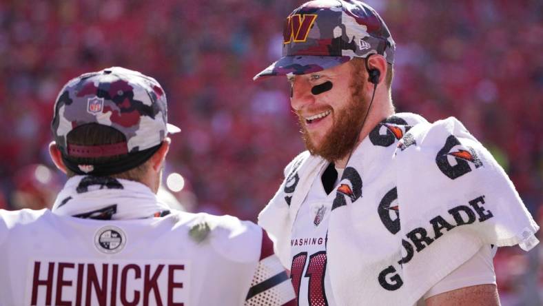 Aug 20, 2022; Kansas City, Missouri, USA; Washington Commanders quarterback Carson Wentz (11) talks with quarterback Taylor Heinicke (4) on the sidelines against the Kansas City Chiefs during the second half at GEHA Field at Arrowhead Stadium. Mandatory Credit: Denny Medley-USA TODAY Sports