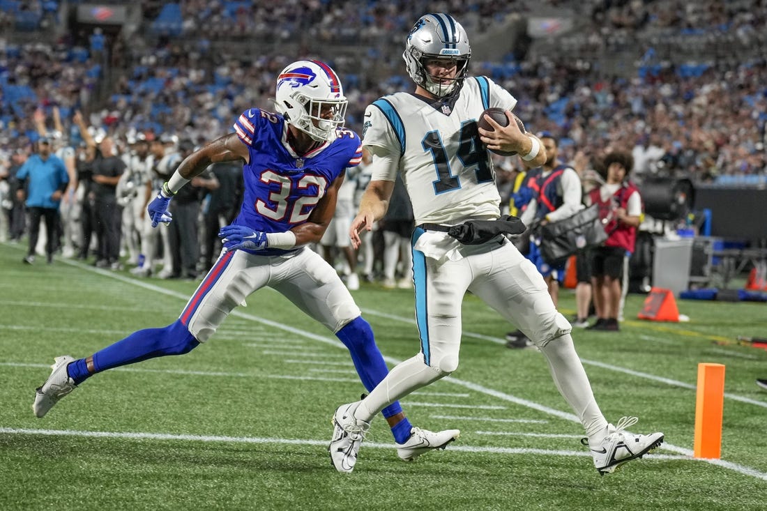 Aug 26, 2022; Charlotte, North Carolina, USA; Carolina Panthers quarterback Sam Darnold (14) scores a touchdown while defended by Buffalo Bills cornerback Jordan Miller (32) during the second half at Bank of America Stadium. Mandatory Credit: Jim Dedmon-USA TODAY Sports