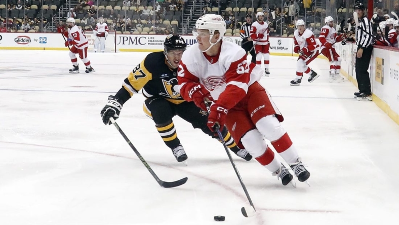 Sep 27, 2022; Pittsburgh, Pennsylvania, USA;  Detroit Red Wings left wing Jonatan Berggren (52) moves the puck ahead of Pittsburgh Penguins center Sidney Crosby (87) during the second period at PPG Paints Arena. Mandatory Credit: Charles LeClaire-USA TODAY Sports