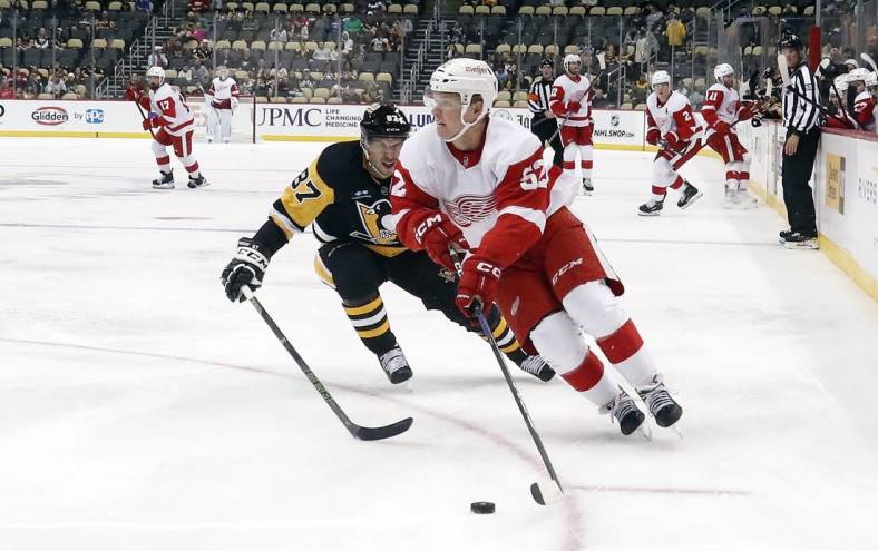Sep 27, 2022; Pittsburgh, Pennsylvania, USA;  Detroit Red Wings left wing Jonatan Berggren (52) moves the puck ahead of Pittsburgh Penguins center Sidney Crosby (87) during the second period at PPG Paints Arena. Mandatory Credit: Charles LeClaire-USA TODAY Sports