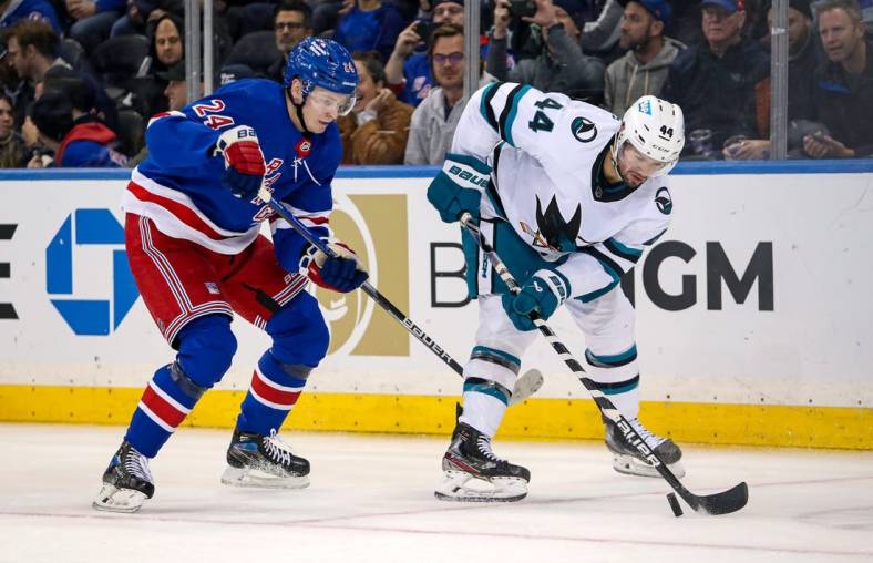 Oct 20, 2022; New York, New York, USA; San Jose Sharks defenseman Marc-Edouard Vlasic (44) and New York Rangers right wing Kaapo Kakko (24) fight for the puck during the third period at Madison Square Garden. Mandatory Credit: Danny Wild-USA TODAY Sports
