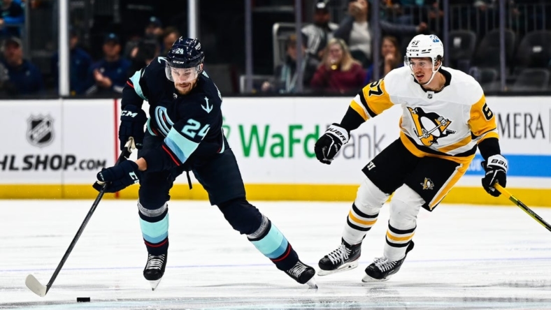 Oct 29, 2022; Seattle, Washington, USA; Seattle Kraken defenseman Jamie Oleksiak (24) controls the puck against Pittsburgh Penguins right wing Rickard Rakell (67) during the second period at Climate Pledge Arena. Seattle won 3-1. Mandatory Credit: Steven Bisig-USA TODAY Sports