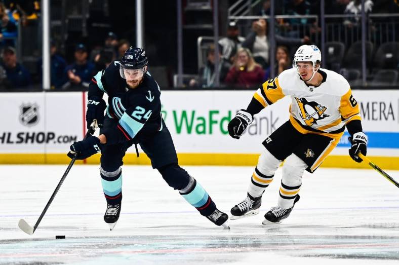 Oct 29, 2022; Seattle, Washington, USA; Seattle Kraken defenseman Jamie Oleksiak (24) controls the puck against Pittsburgh Penguins right wing Rickard Rakell (67) during the second period at Climate Pledge Arena. Seattle won 3-1. Mandatory Credit: Steven Bisig-USA TODAY Sports