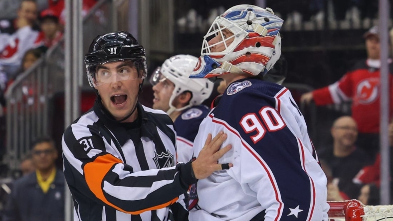 Oct 30, 2022; Newark, New Jersey, USA; Referee Michael Markovic (31) holds back Columbus Blue Jackets goaltender Elvis Merzlikins (90) during the second period of their game against the New Jersey Devils at Prudential Center. Mandatory Credit: Ed Mulholland-USA TODAY Sports