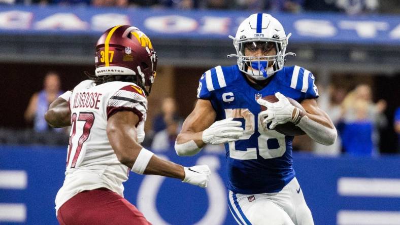 Oct 30, 2022; Indianapolis, Indiana, USA; Indianapolis Colts running back Jonathan Taylor (28) runs the ball while Washington Commanders cornerback Rachad Wildgoose (37) defends in the second half at Lucas Oil Stadium. Mandatory Credit: Trevor Ruszkowski-USA TODAY Sports