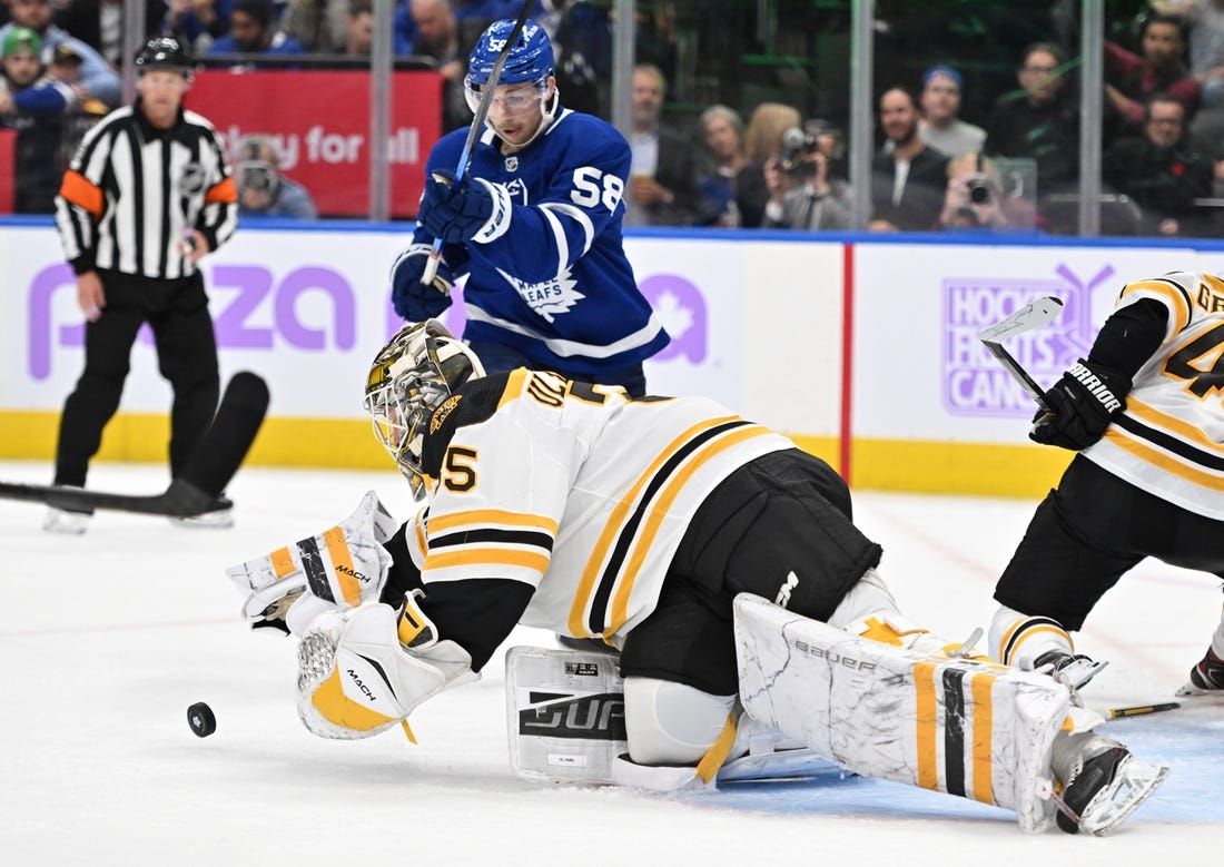 Nov 5, 2022; Toronto, Ontario, CAN; Boston Bruins goalie Linus Ullmark (35) dives to reach a loose puck ahead of Toronto Maple Leafs forward Michael Bunting (58) in the second period at Scotiabank Arena. Mandatory Credit: Dan Hamilton-USA TODAY Sports
