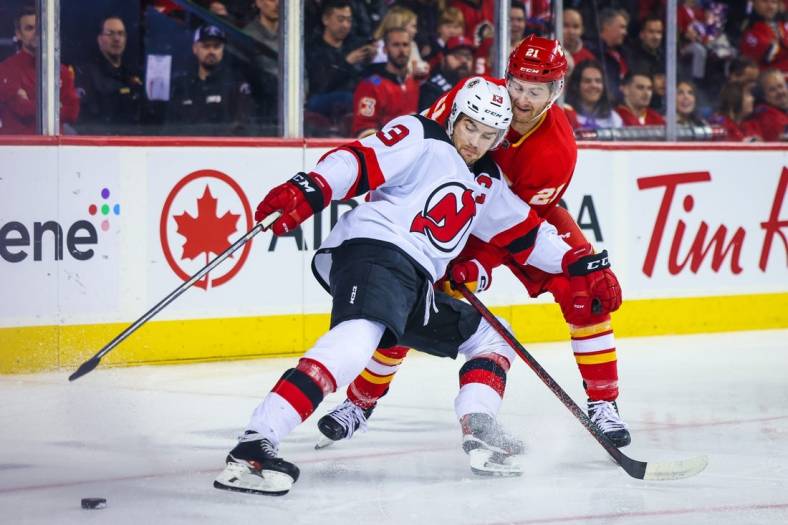 Nov 5, 2022; Calgary, Alberta, CAN; New Jersey Devils center Nico Hischier (13) and Calgary Flames center Kevin Rooney (21) battle for the puck during the first period at Scotiabank Saddledome. Mandatory Credit: Sergei Belski-USA TODAY Sports
