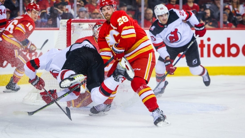 Nov 5, 2022; Calgary, Alberta, CAN; Calgary Flames center Elias Lindholm (28) and New Jersey Devils right wing Nathan Bastian (14) battle for the puck during the first period at Scotiabank Saddledome. Mandatory Credit: Sergei Belski-USA TODAY Sports