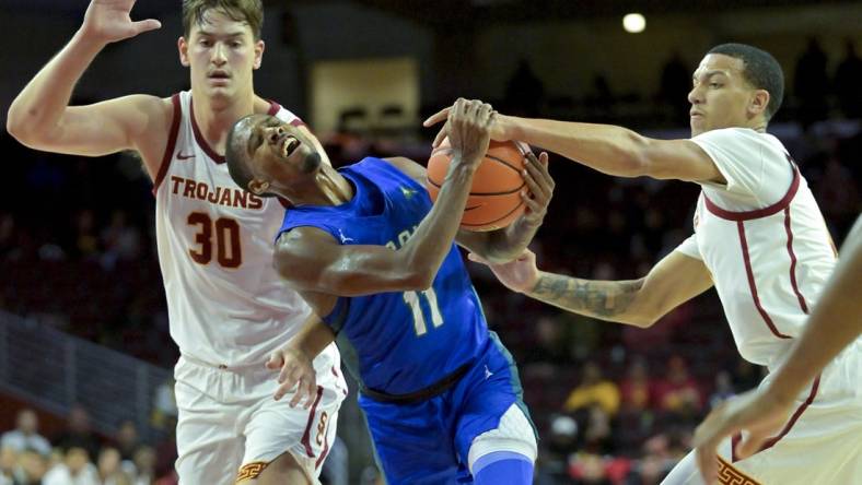 Nov 7, 2022; Los Angeles, California, USA; Florida Gulf Coast Eagles guard Isaiah Thompson (11) is defended by USC Trojans forward Harrison Hornery (30) and forward Kobe Johnson (0) as he drives to the basket in the second half at Galen Center. Mandatory Credit: Jayne Kamin-Oncea-USA TODAY Sports