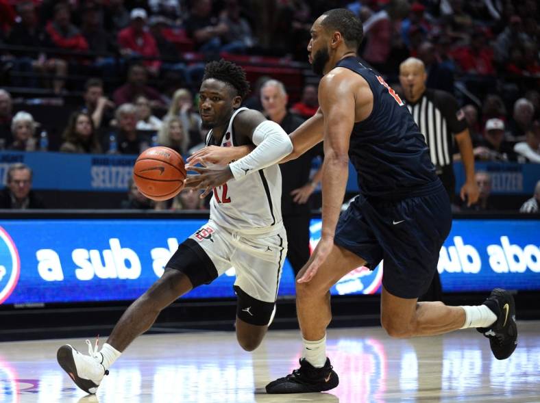 Nov 7, 2022; San Diego, California, USA; San Diego State Aztecs guard Darrion Trammell (12) dribbles the ball while defended by Cal State Fullerton Titans forward Vincent Lee (13) during the second half at Viejas Arena. Mandatory Credit: Orlando Ramirez-USA TODAY Sports