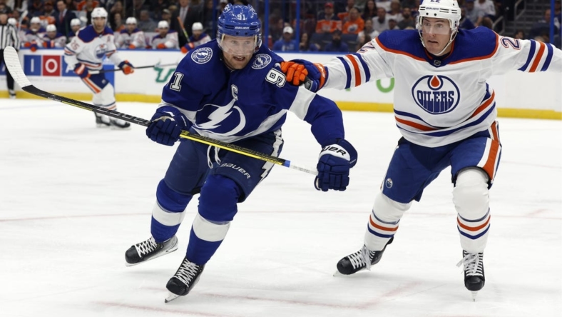 Nov 8, 2022; Tampa, Florida, USA; Tampa Bay Lightning center Steven Stamkos (91) and Edmonton Oilers defenseman Tyson Barrie (22) skate after a loose puck during the first period at Amalie Arena. Mandatory Credit: Kim Klement-USA TODAY Sports