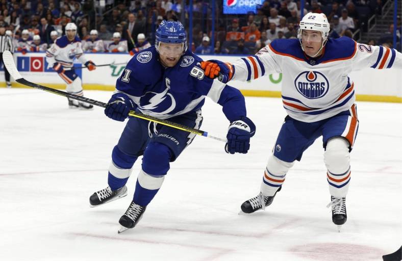 Nov 8, 2022; Tampa, Florida, USA; Tampa Bay Lightning center Steven Stamkos (91) and Edmonton Oilers defenseman Tyson Barrie (22) skate after a loose puck during the first period at Amalie Arena. Mandatory Credit: Kim Klement-USA TODAY Sports