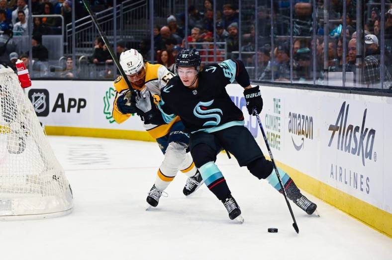 Nov 8, 2022; Seattle, Washington, USA; Seattle Kraken center Morgan Geekie (67) advances the puck while being defended by Nashville Predators defenseman Dante Fabbro (57) during the first period at Climate Pledge Arena. Mandatory Credit: Steven Bisig-USA TODAY Sports