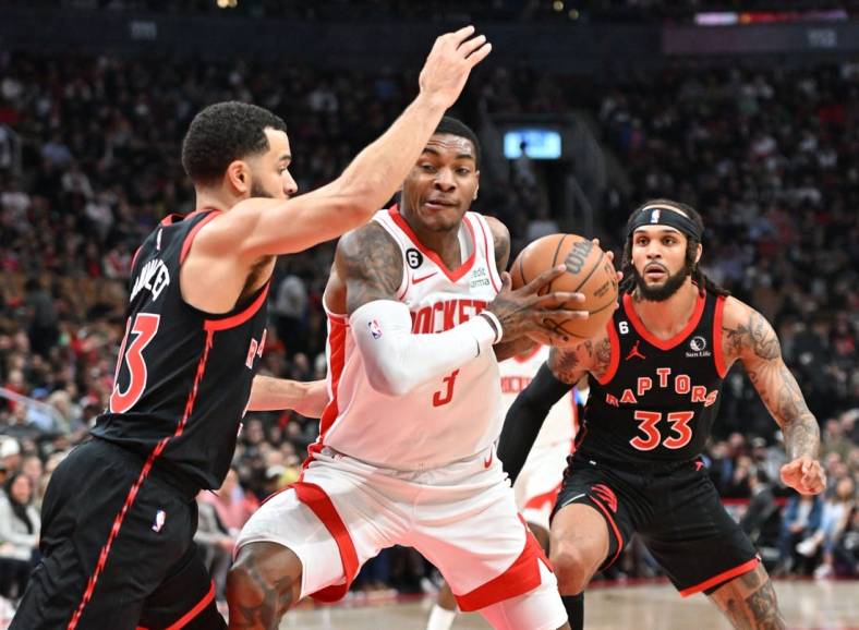 Nov 9, 2022; Toronto, Ontario, CAN;  Houston Rockets guard Kevin Porter Jr. (3) tries to get past Toronto Raptors guards Fred VanVleet (23) and Gary Trent Jr. (33) in the first half at Scotiabank Arena. Mandatory Credit: Dan Hamilton-USA TODAY Sports