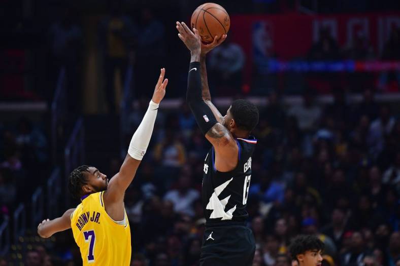 Nov 9, 2022; Los Angeles, California, USA; Los Angeles Clippers guard Paul George (13) shoots against Los Angeles Lakers forward Troy Brown Jr. (7) during the first half at Crypto.com Arena. Mandatory Credit: Gary A. Vasquez-USA TODAY Sports