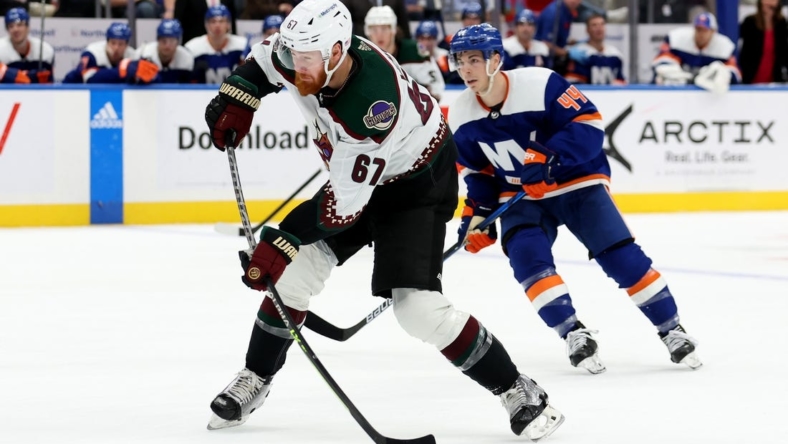 Nov 10, 2022; Elmont, New York, USA; Arizona Coyotes left wing Lawson Crouse (67) takes a shot in front of New York Islanders center Jean-Gabriel Pageau (44) during the third period at UBS Arena. Mandatory Credit: Brad Penner-USA TODAY Sports