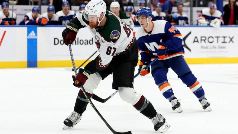 Nov 10, 2022; Elmont, New York, USA; Arizona Coyotes left wing Lawson Crouse (67) takes a shot in front of New York Islanders center Jean-Gabriel Pageau (44) during the third period at UBS Arena. Mandatory Credit: Brad Penner-USA TODAY Sports