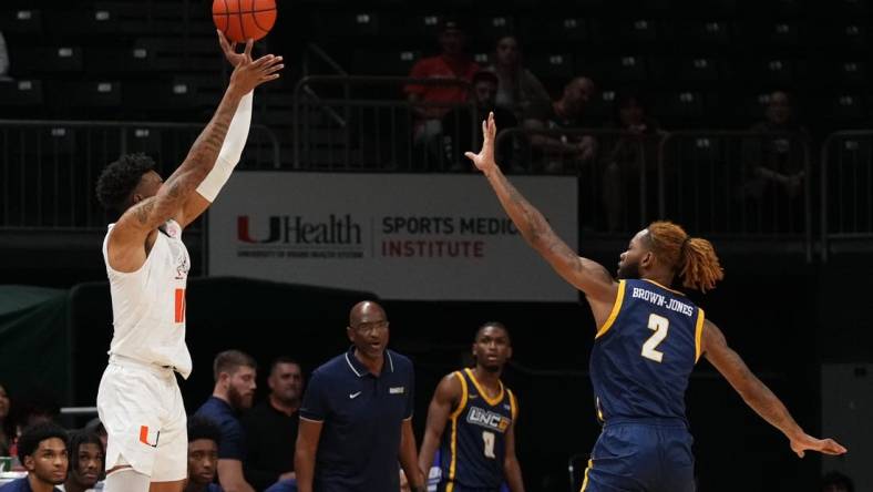 Nov 11, 2022; Coral Gables, Florida, USA; Miami Hurricanes guard Jordan Miller (11) attempts a three point shot over UNC Greensboro Spartans forward Mikeal Brown-Jones (2) during the first half at Watsco Center. Mandatory Credit: Jasen Vinlove-USA TODAY Sports