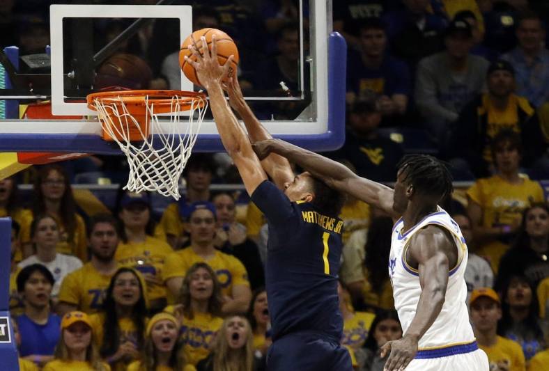 Nov 11, 2022; Pittsburgh, Pennsylvania, USA;  West Virginia Mountaineers forward Emmitt Matthews Jr. (1) dunks the ball past Pittsburgh Panthers center Federiko Federiko (right) during the first half at the Petersen Events Center. Mandatory Credit: Charles LeClaire-USA TODAY Sports