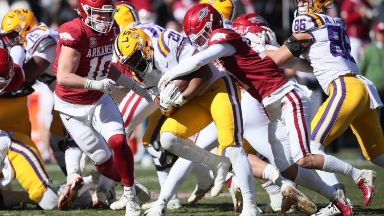 Nov 12, 2022; Fayetteville, Arkansas, USA; LSU Tigers running back Noah Cain (21) is tackled by Arkansas Razorbacks defensive back Hudson Clark (17) and linebacker Bumper Poole (10) during the second quarter at Donald W. Reynolds Razorback Stadium. Mandatory Credit: Nelson Chenault-USA TODAY Sports