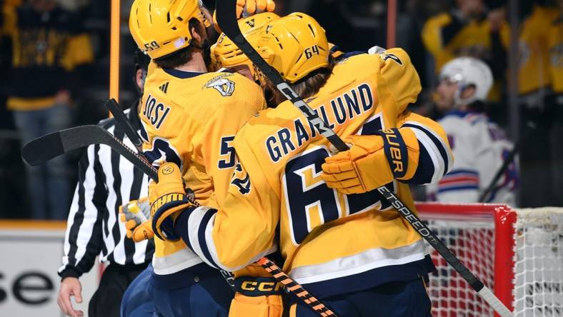 Nov 12, 2022; Nashville, Tennessee, USA; Nashville Predators center Juuso Parssinen (75) celebrates with defenseman Roman Josi (59) and center Mikael Granlund (64) after scoring his first career goal during the first period against the New York Rangers at Bridgestone Arena. Mandatory Credit: Christopher Hanewinckel-USA TODAY Sports