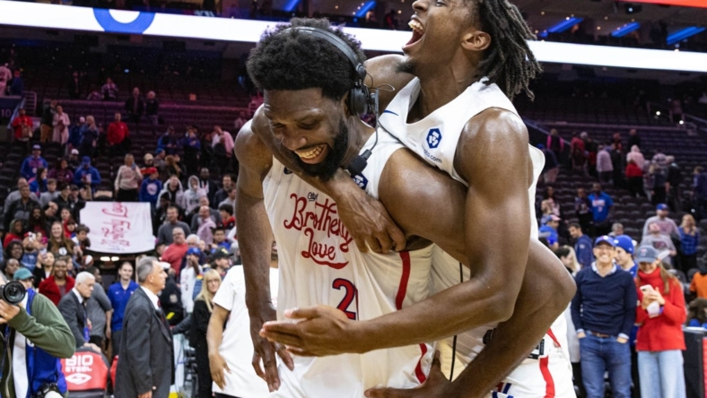 Nov 13, 2022; Philadelphia, Pennsylvania, USA; Philadelphia 76ers guard Tyrese Maxey (0) leaps onto center Joel Embiid (21) after Embiids 59 points in a victory against the Utah Jazz at Wells Fargo Center. Mandatory Credit: Bill Streicher-USA TODAY Sports