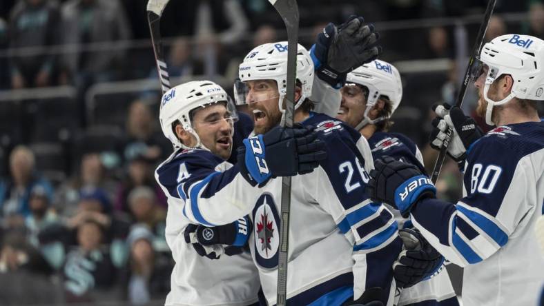 Nov 13, 2022; Seattle, Washington, USA; Winnipeg Jets forward Blake Wheeler (26) is congratulated by teammates including defenseman Neal Pionk (4), forward Mark Scheifele (55) and forward Pierre-Luc Dubois (80) during the third period against the Seattle Kraken at Climate Pledge Arena. Mandatory Credit: Stephen Brashear-USA TODAY Sports