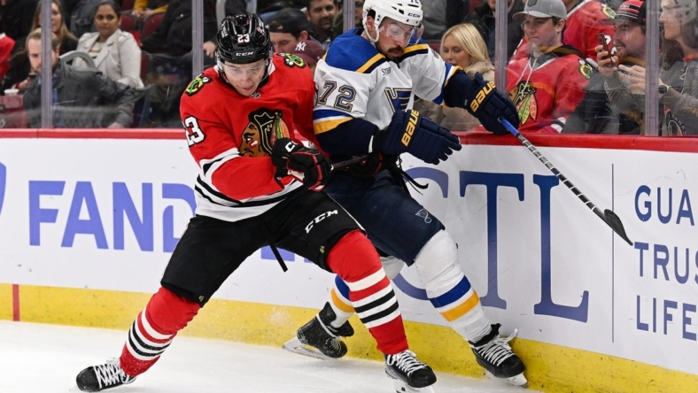 Nov 16, 2022; Chicago, Illinois, USA;  Chicago Blackhawks forward Philipp Kurashev (23) battles with St. Louis Blues defenseman Justin Faulk (72) for control of the puck in the second period at the United Center. Mandatory Credit: Jamie Sabau-USA TODAY Sports