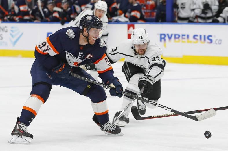 Nov 16, 2022; Edmonton, Alberta, CAN; Los Angeles Kings forward Viktor Arvidsson (33) tries to knock the puck away from Edmonton Oilers forward Connor McDavid (97) during the first period at Rogers Place. Mandatory Credit: Perry Nelson-USA TODAY Sports