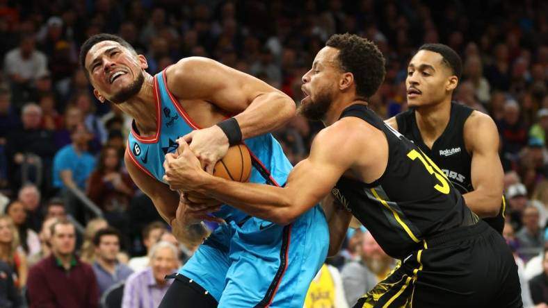 Nov 16, 2022; Phoenix, Arizona, USA; Phoenix Suns guard Devin Booker (1) battles for the ball against Golden State Warriors guard Stephen Curry (30) in the first half at Footprint Center. Mandatory Credit: Mark J. Rebilas-USA TODAY Sports