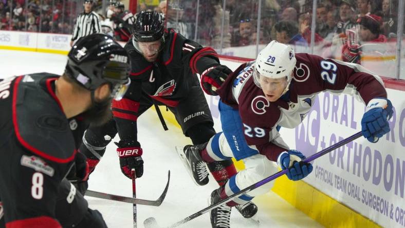 Nov 17, 2022; Raleigh, North Carolina, USA; Carolina Hurricanes center Jordan Staal (11) checks Colorado Avalanche center Nathan MacKinnon (29) during the first period at PNC Arena. Mandatory Credit: James Guillory-USA TODAY Sports