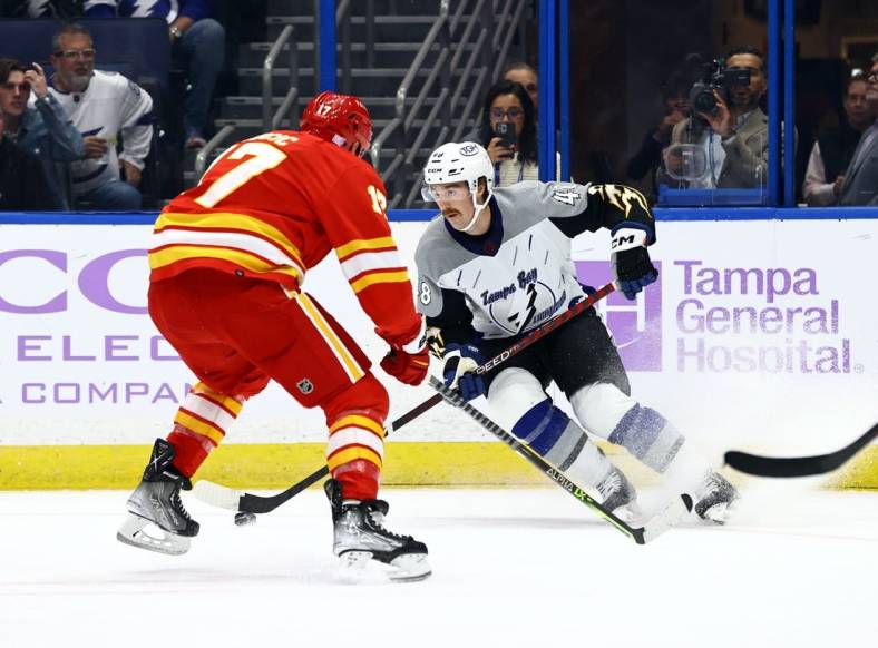 Nov 17, 2022; Tampa, Florida, USA; Tampa Bay Lightning defenseman Nick Perbix (48) skates with the puck as Calgary Flames left wing Milan Lucic (17) defends during the first period at Amalie Arena. Mandatory Credit: Kim Klement-USA TODAY Sports