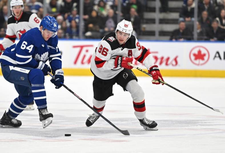 Nov 17, 2022; Toronto, Ontario, CAN; New Jersey Devils forward Jack Hughes (86) moves the puck past Toronto Maple Leafs forward David Kampf (64) in the first period at Scotiabank Arena. Mandatory Credit: Dan Hamilton-USA TODAY Sports