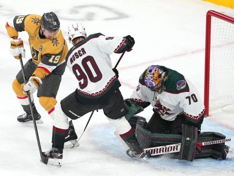 Nov 17, 2022; Las Vegas, Nevada, USA; Arizona Coyotes goaltender Karel Vejmelka (70) makes a save against Vegas Golden Knights right wing Reilly Smith (19) as Coyotes defenseman J.J. Moser (90) helps protect the net during the first period at T-Mobile Arena. Mandatory Credit: Stephen R. Sylvanie-USA TODAY Sports