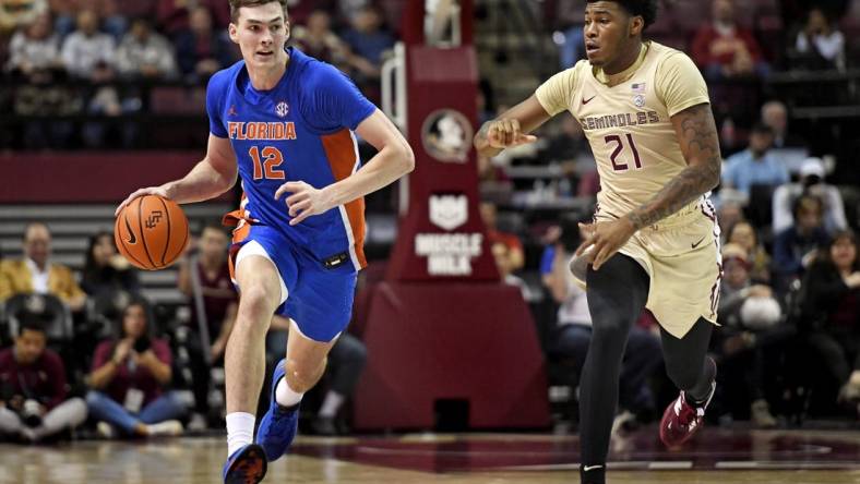 Nov 18, 2022; Tallahassee, Florida, USA; Florida Gators forward Colin Castleton (12) drives up the court past Florida State Seminoles guard Cam'Ron Fletcher (21) during the second half at Donald L. Tucker Center. Mandatory Credit: Melina Myers-USA TODAY Sports