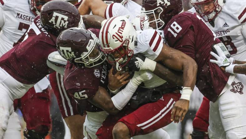 Nov 19, 2022; College Station, Texas, USA; Massachusetts Minutemen running back Ellis Merriweather (7) is tackled by Texas A&M Aggies linebacker Edgerrin Cooper (45) and defensive lineman LT Overton (18) during the first quarter at Kyle Field. Mandatory Credit: Troy Taormina-USA TODAY Sports