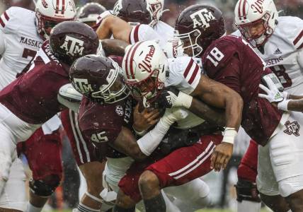 Nov 19, 2022; College Station, Texas, USA; Massachusetts Minutemen running back Ellis Merriweather (7) is tackled by Texas A&M Aggies linebacker Edgerrin Cooper (45) and defensive lineman LT Overton (18) during the first quarter at Kyle Field. Mandatory Credit: Troy Taormina-USA TODAY Sports