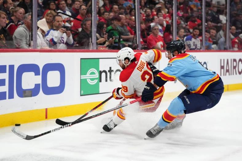 Nov 19, 2022; Sunrise, Florida, USA; Florida Panthers defenseman Aaron Ekblad (5) and Calgary Flames center Dillon Dube (29) battle for a loose puck during the first period at FLA Live Arena. Mandatory Credit: Jasen Vinlove-USA TODAY Sports