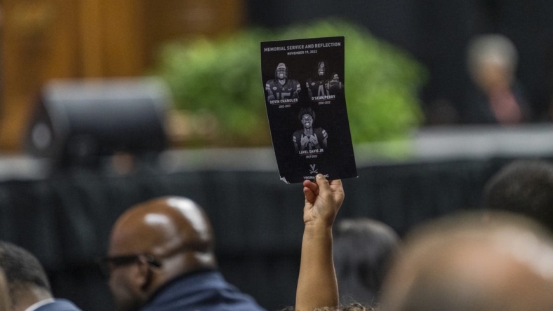 Nov 19, 2022; Charlottesville, Virginia, US; A flyer is held up during the memorial service for three slain University of Virginia football players Lavel Davis Jr., D Sean Perry and Devin Chandler at John Paul Jones Arena. Mandatory Credit: Erin Edgerton/Pool Photo-USA TODAY Sports